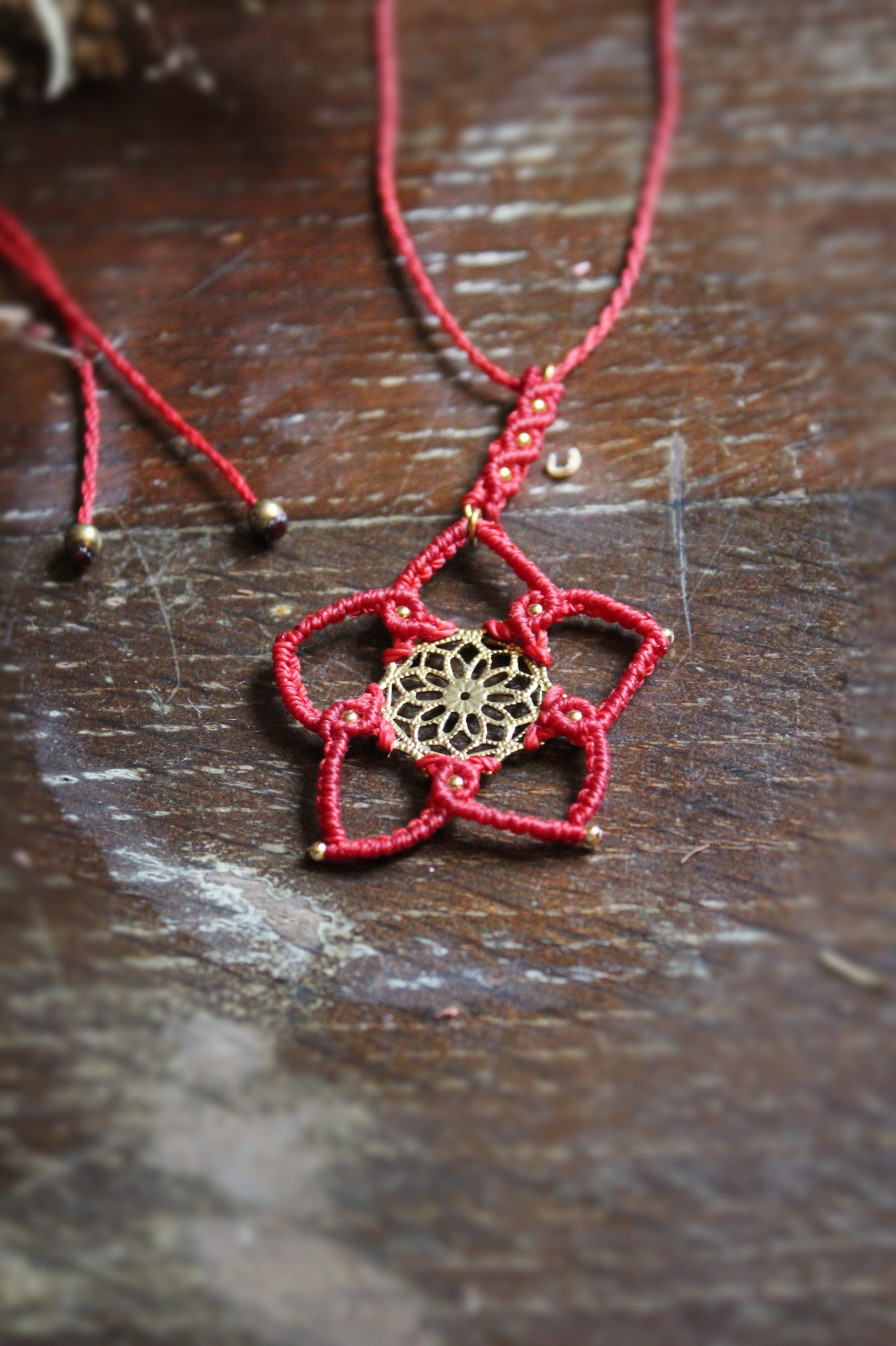 Collier en micro macramé rouge et pièce centrale en laiton représentant une fleur