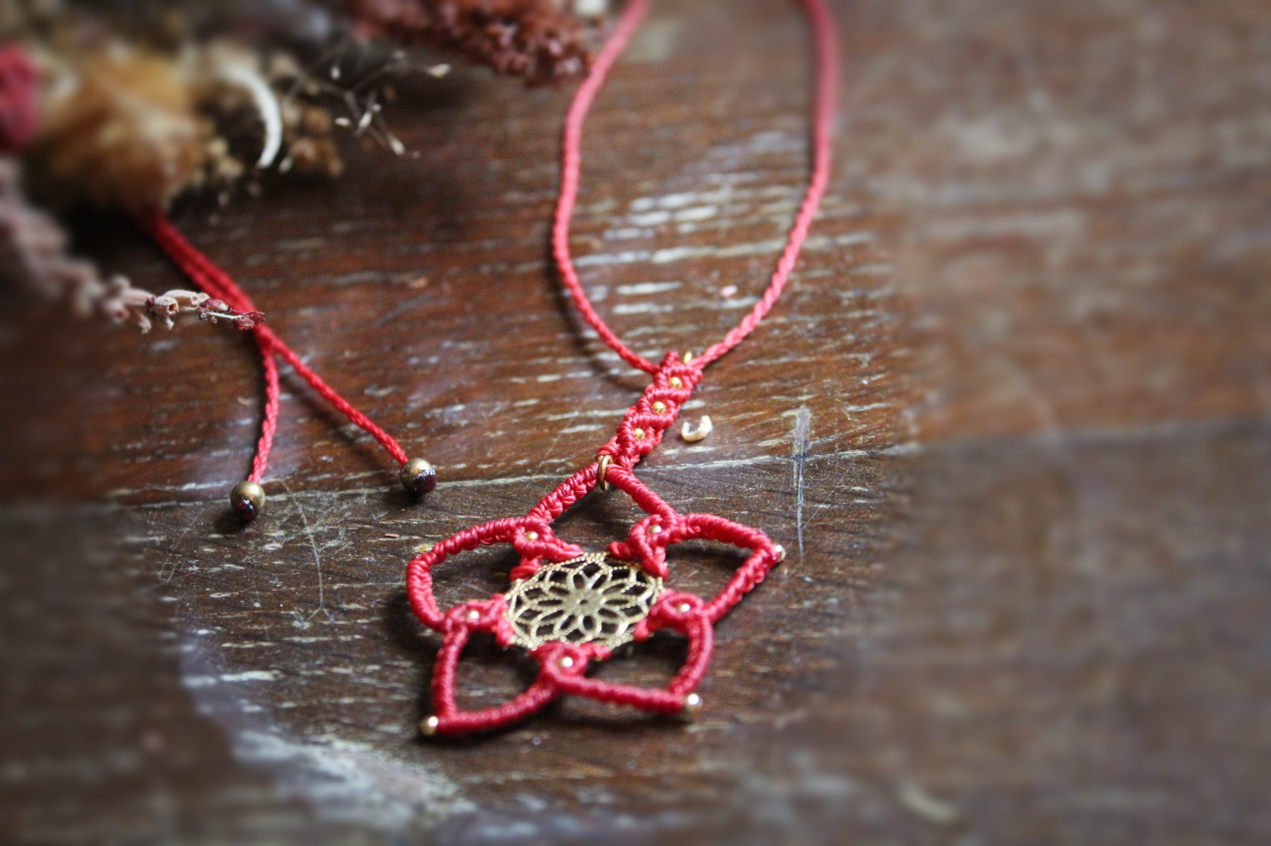 Collier en micro macramé rouge et pièce centrale en laiton représentant une fleur