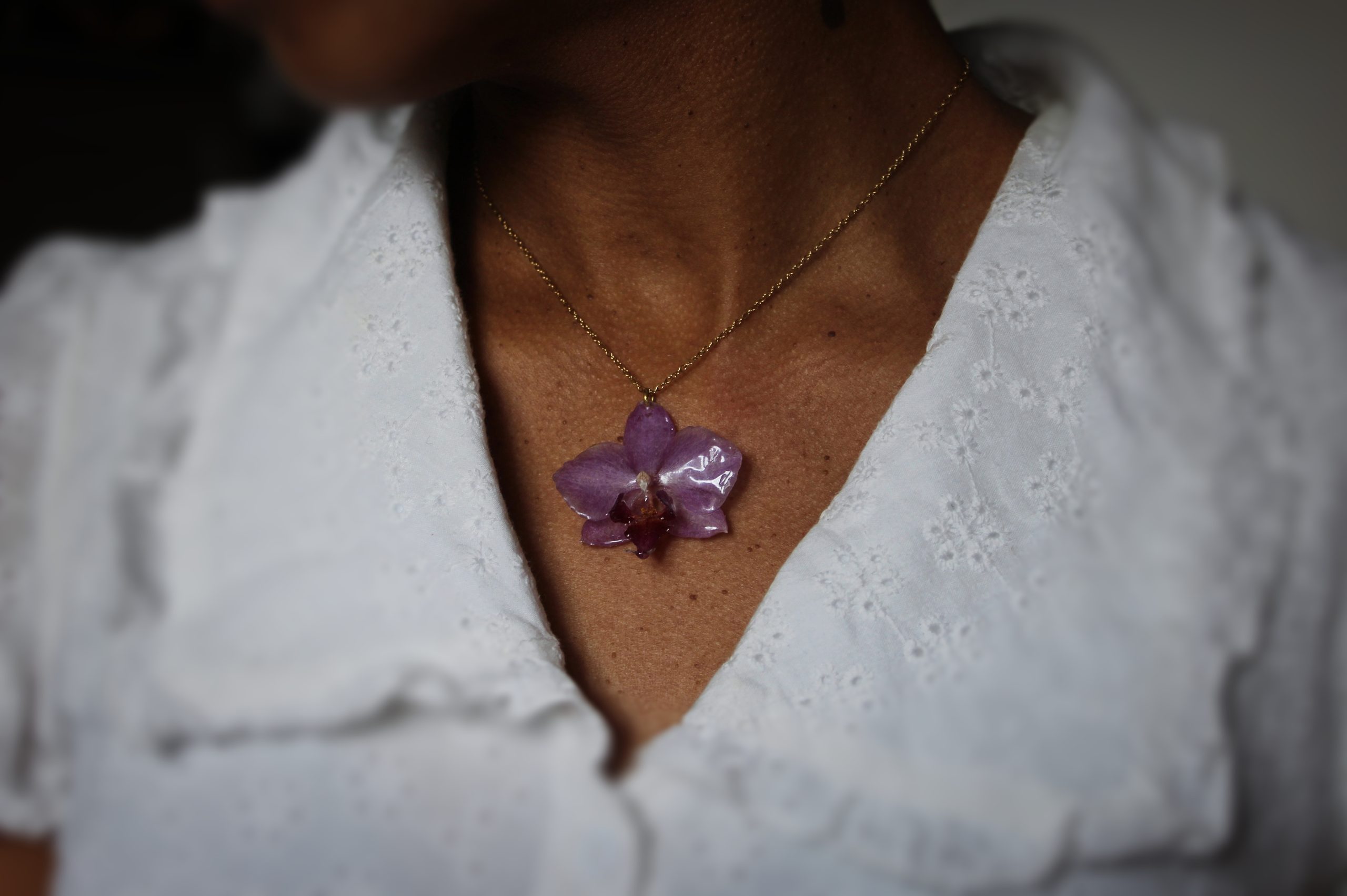Collier porté avec une véritable orchidée résinée et chaîne dorée