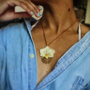 Collier artisanal avec une véritable orchidée naturelle et un pendentif mandala en métal, porté