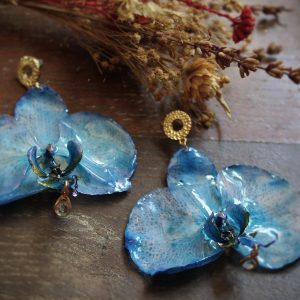 Boucles d'oreilles en orchidées bleues avec breloque dorée et cristal