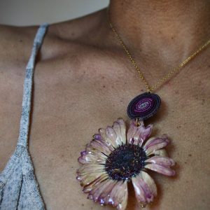 Collier avec une fleur naturelle naturelle rose séchée, monté sur une chaîne dorée avec une pièce tissée en micro-macramé dégradé rose et violet.