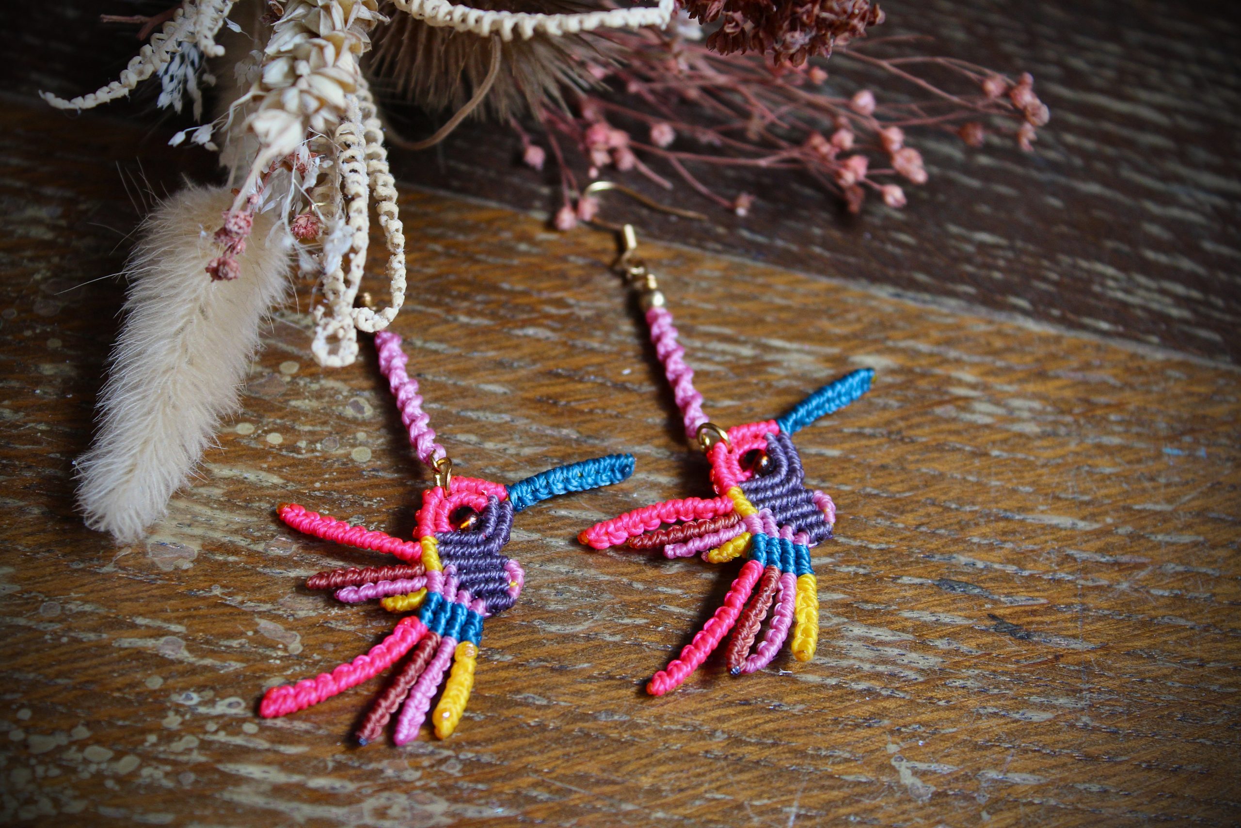 Boucles d'oreilles colibri en micro-macramé multicolore rose, bleu et jaune, faites main par Lessance