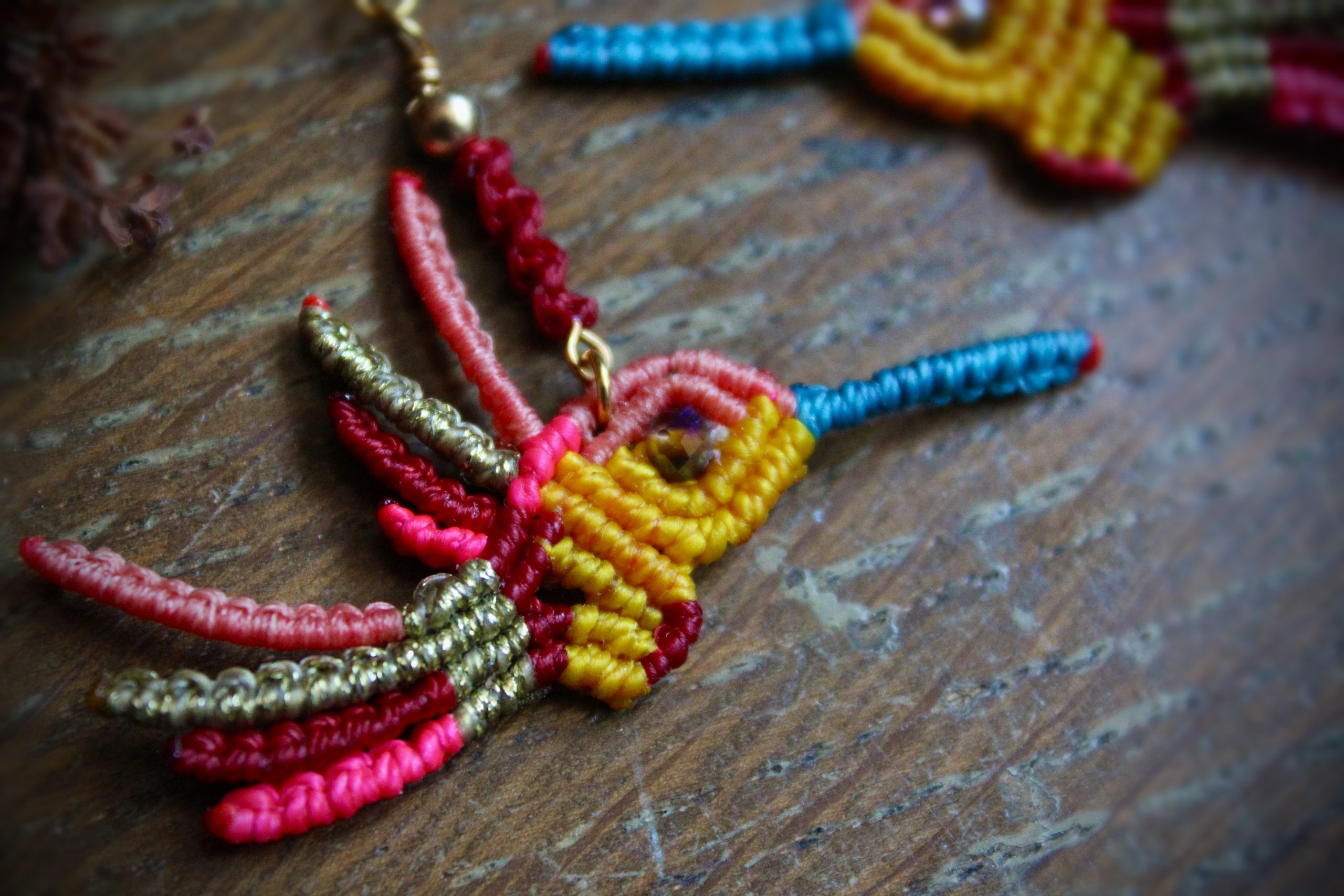Boucles d'oreilles colibri en micro-macramé multicolore rose, bleu et jaune, faites main par Lessance