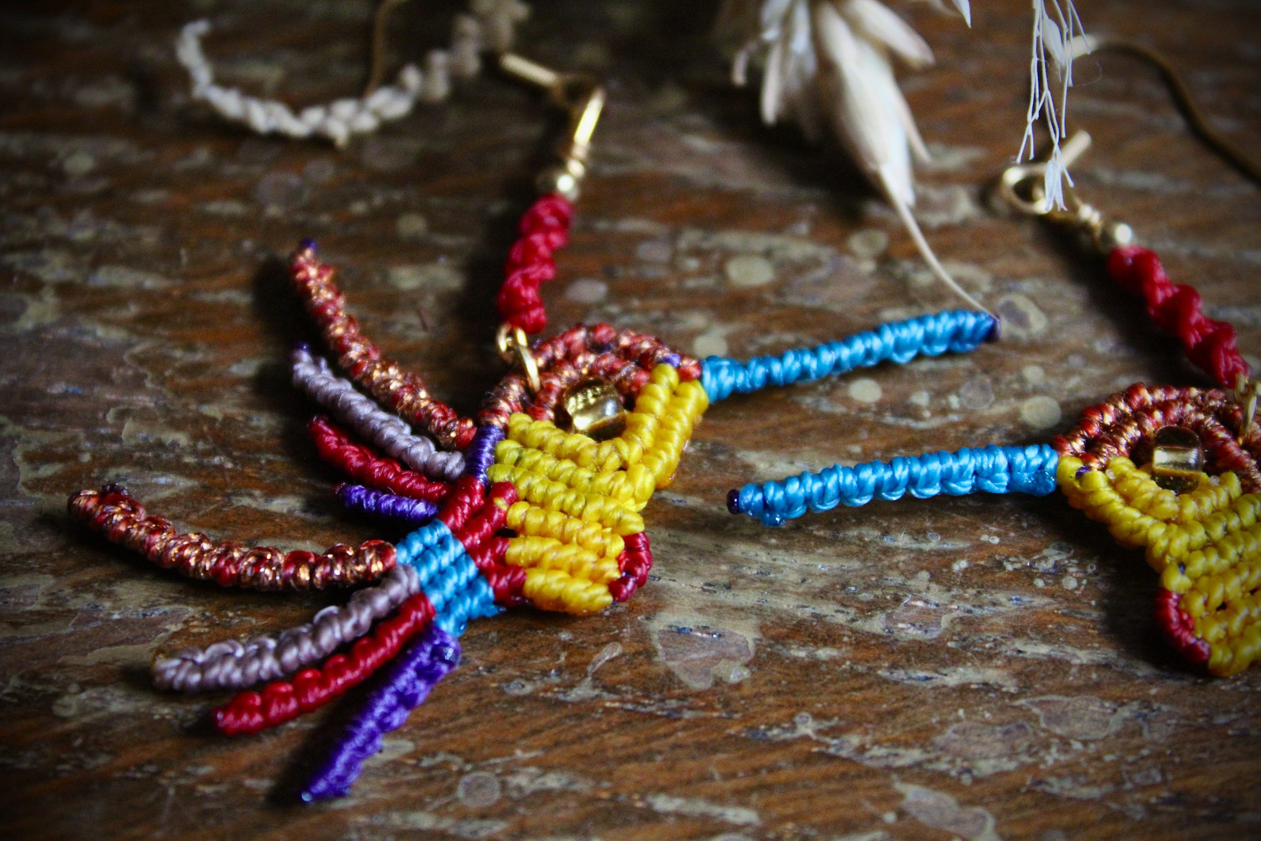 Boucles d'oreilles colibri en micro-macramé multicolore bleu, cuivre et jaune, faites main par Lessance